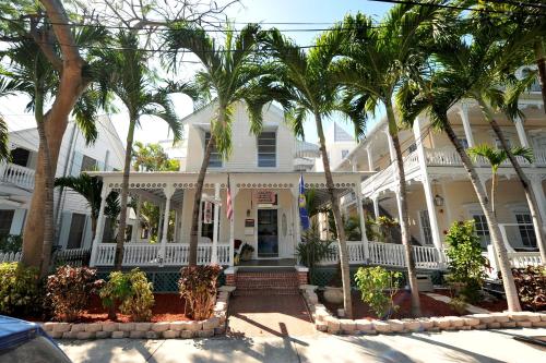 uma casa branca com palmeiras em frente em The Palms Hotel em Key West