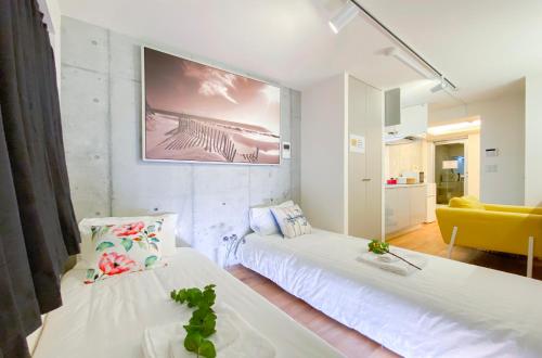 東京にあるjapan house nishishinjukuのベッドが2つと壁にテレビがある部屋