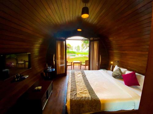 a bedroom with a large bed in a room with a window at Regenta Resort Soma Vine Village Nashik in Nashik