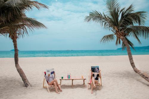 Horizon Resort & Spa Yalong Bay-Yalong Bay Central في سانيا: كانتا جالستين على طاولة على الشاطئ