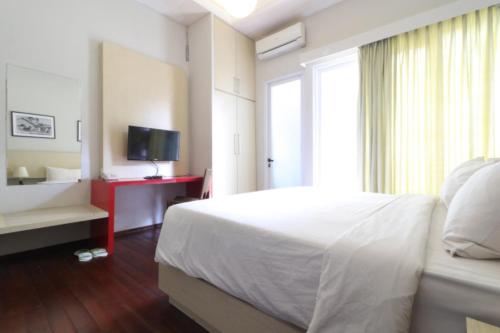 a bedroom with a white bed and a television at Pejaten Valley Residence in Jakarta