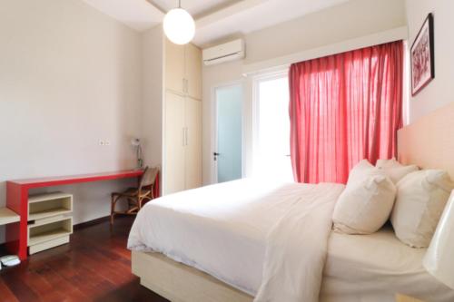 a bedroom with a white bed with a red curtain at Pejaten Valley Residence in Jakarta