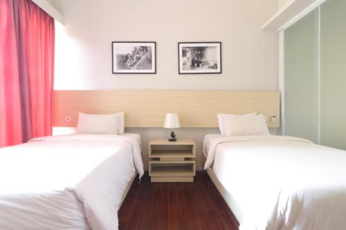 a bedroom with two beds and a table with a lamp at Pejaten Valley Residence in Jakarta