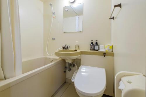 a white bathroom with a toilet and a sink at Nobeoka Royal Hotel in Nobeoka