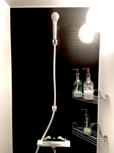 a bathroom with a shower with two glass bottles at Okiya Guest House & Tapas Bar in Kiryu