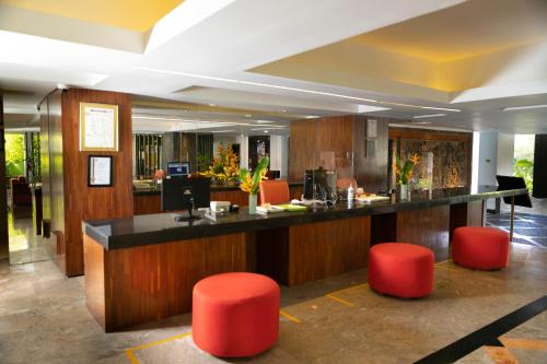 a lobby with a bar with red stools at Prime Plaza Suites Sanur – Bali in Sanur