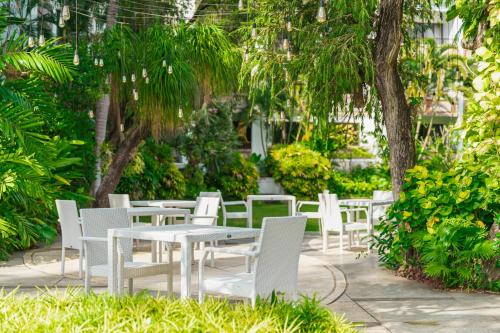 a group of white tables and chairs in a garden at Prime Plaza Suites Sanur – Bali in Sanur
