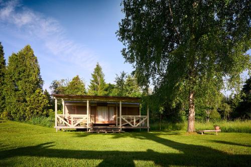 une petite maison dans un champ avec un arbre dans l'établissement maringotka Aluna - České Švýcarsko, à Staré Křečany