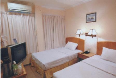 a hotel room with two beds and a television at Hotel City Star in Sandakan