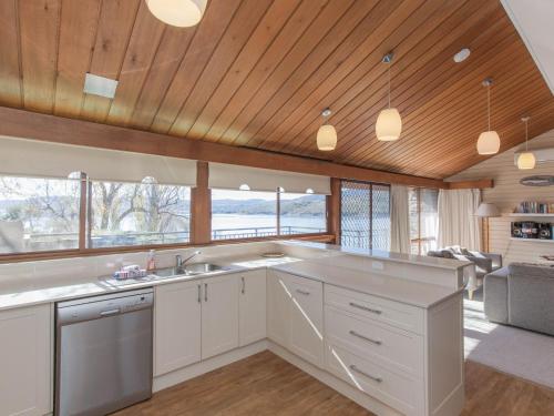 a kitchen with white cabinets and a wooden ceiling at Platypus 19 McLure Circuit in Jindabyne