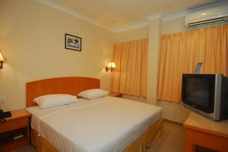 a hotel room with a bed and a tv at Hotel City Star in Sandakan
