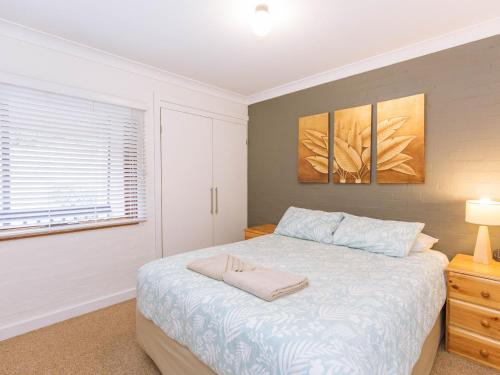 a white bedroom with a bed and a window at Dauphine 1 23 Townsend Street in Jindabyne