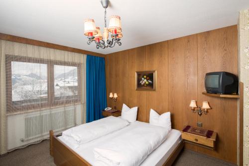 um quarto com uma cama grande e uma televisão em Pension Mühlbachhof em Alpbach