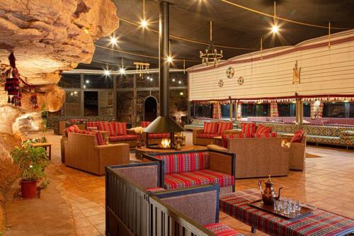 a restaurant with red chairs and tables and a stone wall at Wadi Rum Bedouin Camp in Wadi Rum