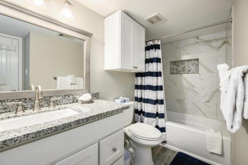 ein Badezimmer mit einem Waschbecken, einem WC und einem Spiegel in der Unterkunft Seascape 1304 Condo in Galveston
