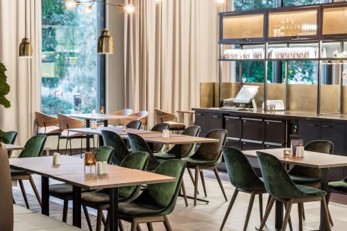 a restaurant with wooden tables and green chairs at Clarion Hotel Sundsvall in Sundsvall
