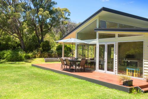 a house with a deck with a table and chairs at Prevelly Beach Retreat in Prevelly