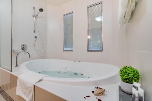 a white bathroom with a tub and a sink at Mercure Albury in Albury