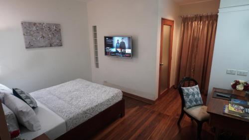 a bedroom with a bed and a tv on the wall at 1775 Adriatico Suites in Manila