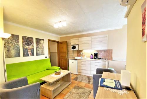 a living room with a green couch and a kitchen at Apartman Siesta Bük in Bük