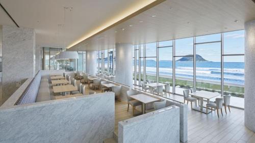 a restaurant with tables and chairs and the ocean at Karatsu Seaside Hotel in Karatsu