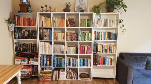 a white book shelf filled with books in a living room at Dom O Niebieskich Okiennicach in Gryfów Śląski
