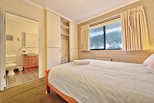 a bedroom with a large white bed and a bathroom at Snow Ski Apartments 16 in Falls Creek