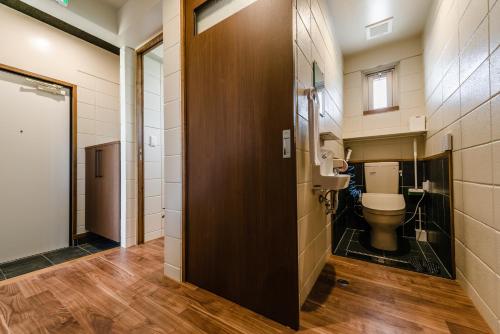 a bathroom with a toilet and a wooden door at LEGO in Uruma