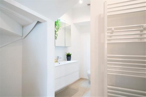 a white bathroom with a toilet and a sink at Saint Pauls Central Residence in Antwerp