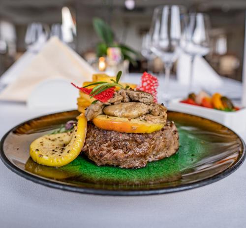 a plate with a hamburger and vegetables on a table at Boutique Odyseja & Spa in Ciechocinek