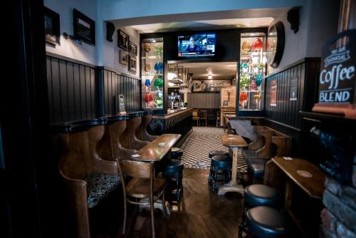 a bar with wooden tables and stools and a tv at Lower Turks Head in Manchester