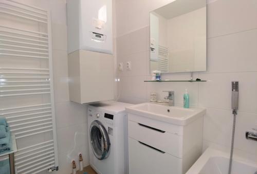 biała łazienka z pralką i umywalką w obiekcie Apartmán Športová w mieście Trnava