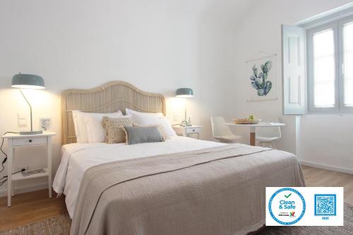 a white bedroom with a large bed and a table at Lavradores Boutique Guesthouse in Évora