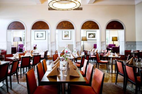 een restaurant met tafels en stoelen en een kroonluchter bij Elite Stadshotellet Karlstad, Hotel & Spa in Karlstad