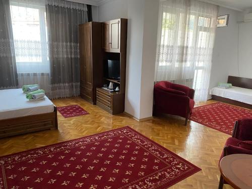 a living room with red rugs and a room with a tv at Family Hotel "May" in Petrich