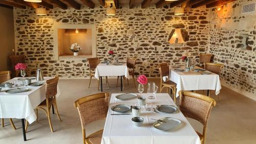 un restaurante con mesas y sillas blancas y una pared de piedra en Maison Fleuriet - Chambres d'hôtes, en Menetou-Râtel
