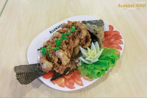 a plate of food with meat and vegetables on a table at Asawann Hotel Nongkhai in Nong Khai