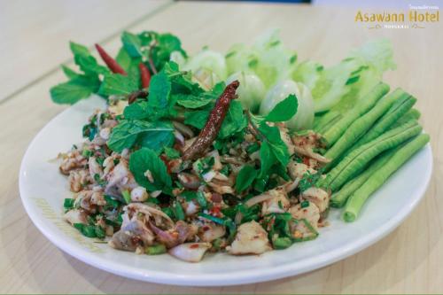 a white plate with a salad with greens and vegetables at Asawann Hotel Nongkhai in Nong Khai