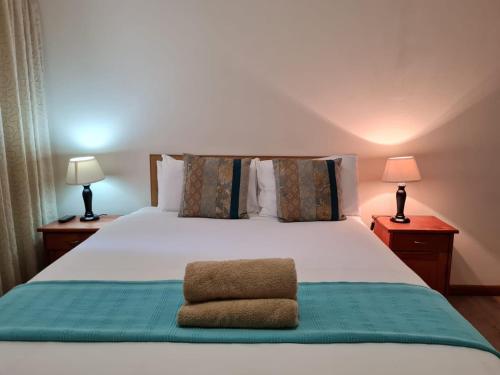 a bedroom with a large white bed with two lamps at Point Village Accommodation - Erin 5 in Mossel Bay