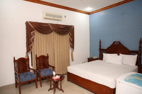 a bedroom with two beds and two chairs and a window at Hotel OR Odyssey Residence in Multan