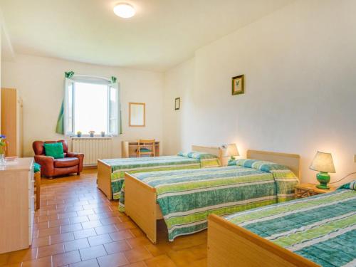a hotel room with three beds and a chair at Apartment Tegola by Interhome in Pogi
