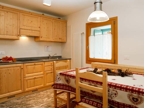 een keuken met houten kasten en een tafel en een raam bij Apartment Cjase Fravins-1 by Interhome in Raveo