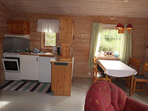a kitchen with white appliances and a table in a cabin at Holiday Home Solbakken - FJS547 by Interhome in Gjølanger