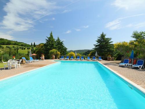 uma grande piscina com cadeiras e cadeiras azuis em Holiday Home Poggio Velluto by Interhome em Seggiano