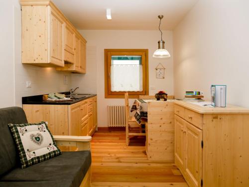a kitchen with wooden cabinets and a couch in a room at Apartment Cjase Fravins-3 by Interhome in Raveo