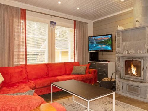 ein Wohnzimmer mit einem roten Sofa und einem Kamin in der Unterkunft Holiday Home Jutapirtti by Interhome in Levi