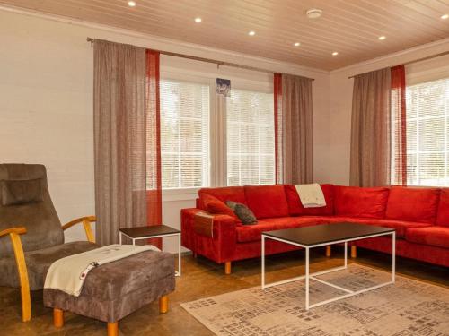 a living room with a red couch and a chair at Holiday Home Jutapirtti by Interhome in Levi