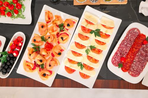 a table topped with white plates filled with different types of food at Hotel Villa Harmony in Split