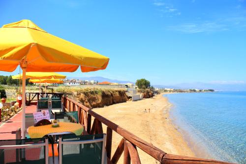 a beach with tables and umbrellas next to the ocean at Alkionis Beach Hotel Apartments in Sfakaki