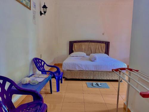 a bedroom with a bed and a chair and a table at Hotel Rembulan in Tebingtinggi